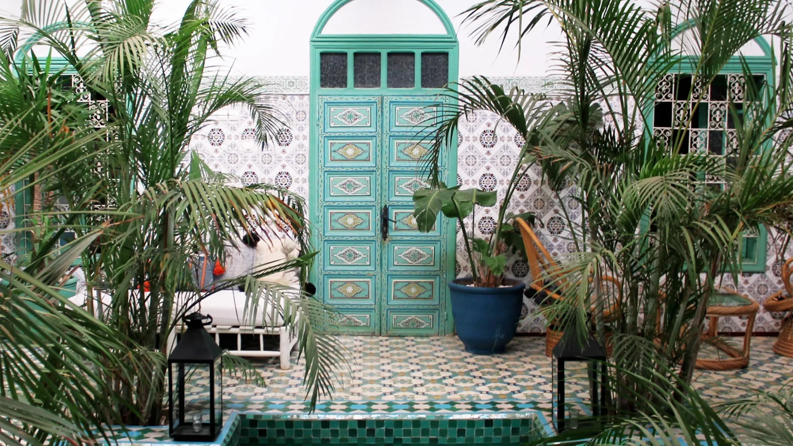 Patio d un riad traditionnel de Marrakech avec porte turquoise et palmiers